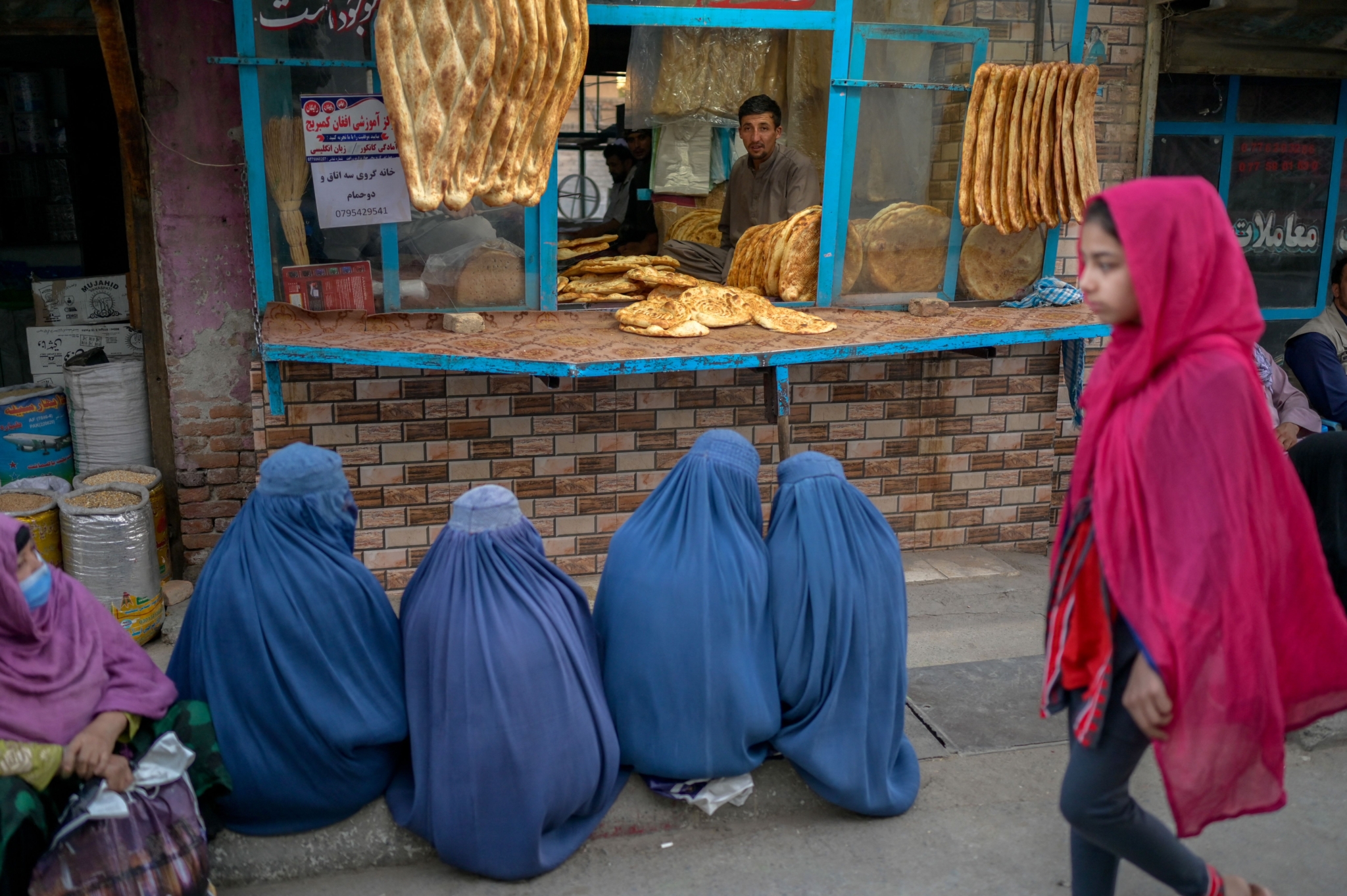 Burqa-clad women wait for free bread in front of a bakery in Kabul on September 16, 2021.