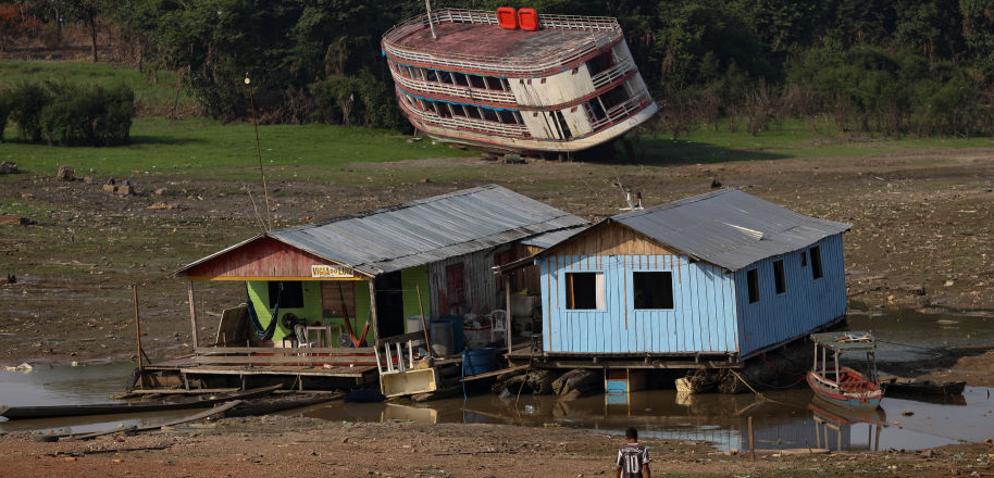 A boat and two homes rest along a dry river bed