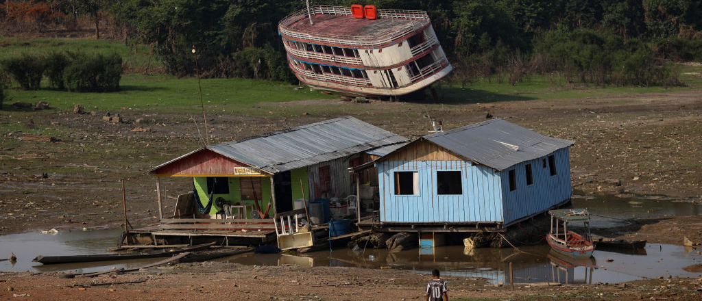 A boat and two homes rest along a dry river bed