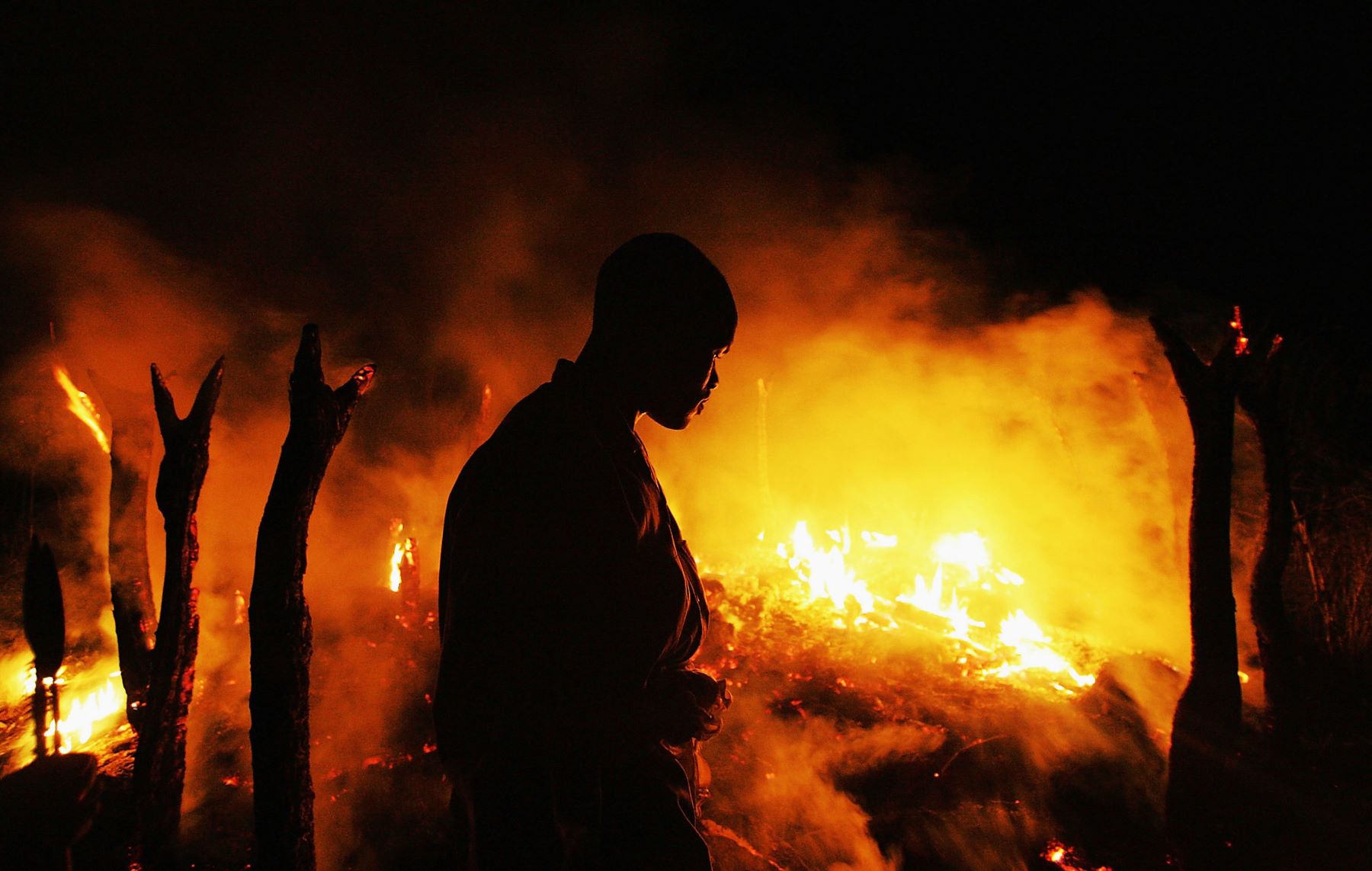 A Sudanese rebel fighter from the Justice and Equality Movement (JEM) sombrely watches the abandoned village of Chero Kasi burn less than an hour after Janjaweed militiamen set it ablaze in the violence plagued Darfur region September 7, 2004. Photo by Scott Nelson/Getty Images.