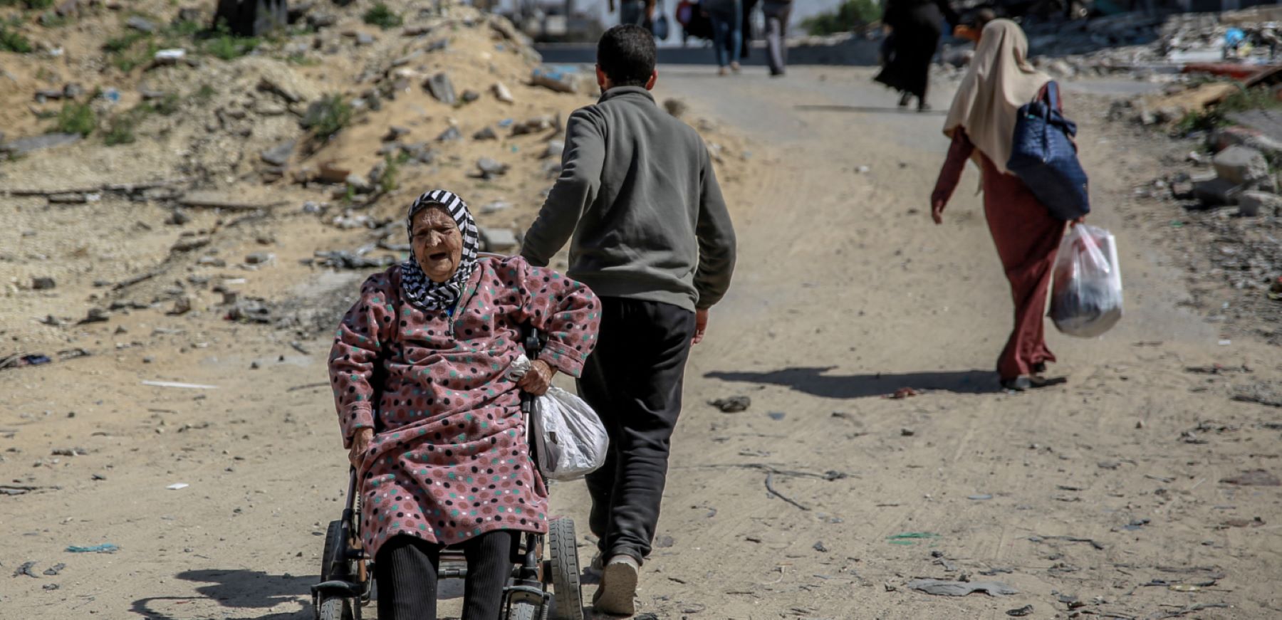 A man pulls an elderly Palestinian woman on a wheelchair as displaced families move in Gaza City, on March 25, 2024, amid the ongoing conflict between Israel and the Palestinian Hamas movement. Photo by AFP via Getty Images.
