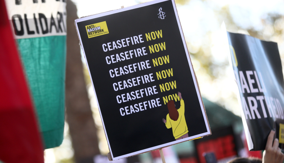 A black sign with the text "Ceasefire Now" written on it six times.