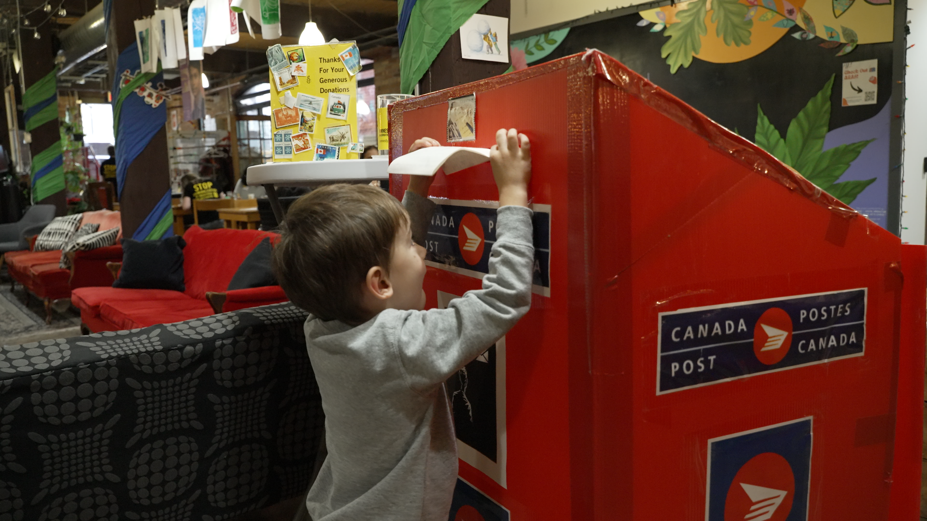 A little kid putting a letter inside a mailbox at Write for Rights event in Canada
