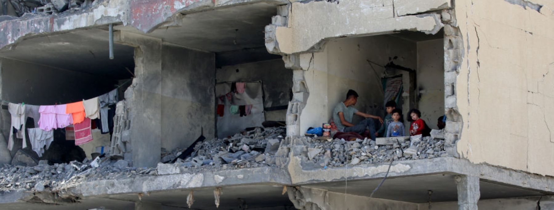 A Palestinian man and his children sit in a destroyed room following the targeting or a residential building by an Israeli airstrike in Rafah in the southern Gaza Strip on May 22, 2024. Photo by EYAD BABA/AFP via Getty Images.