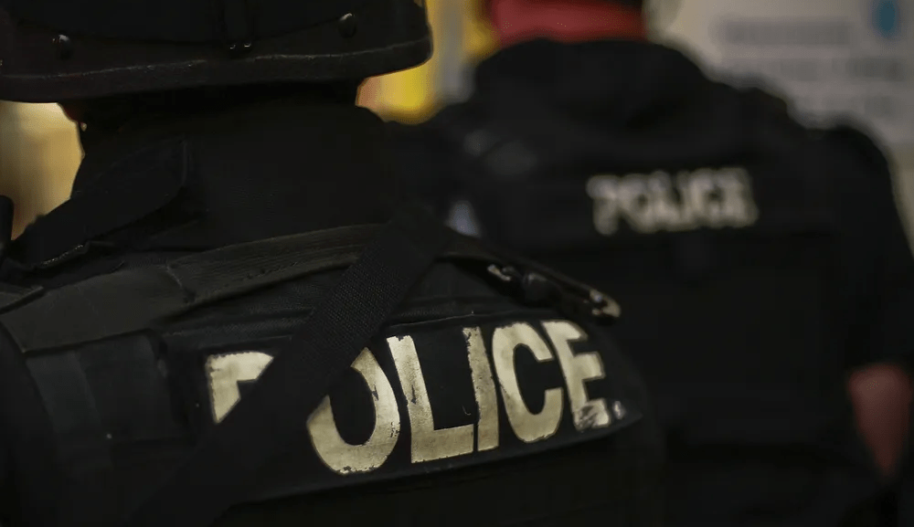 The back of a police officer's black tactical uniform with the word "police" spelled out in capital letters