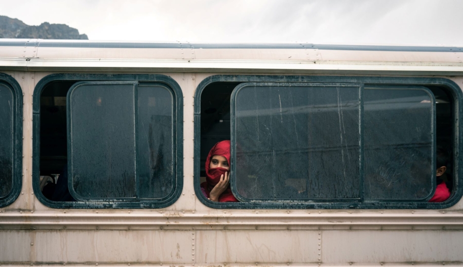 Woman sits in a bus going to a camp set up for returnees who have been deported or coerced into leaving Pakistan, at the Torkham border crossing in Nangarhar province, Eastern Afghanistan. Photo by The Washington Post.