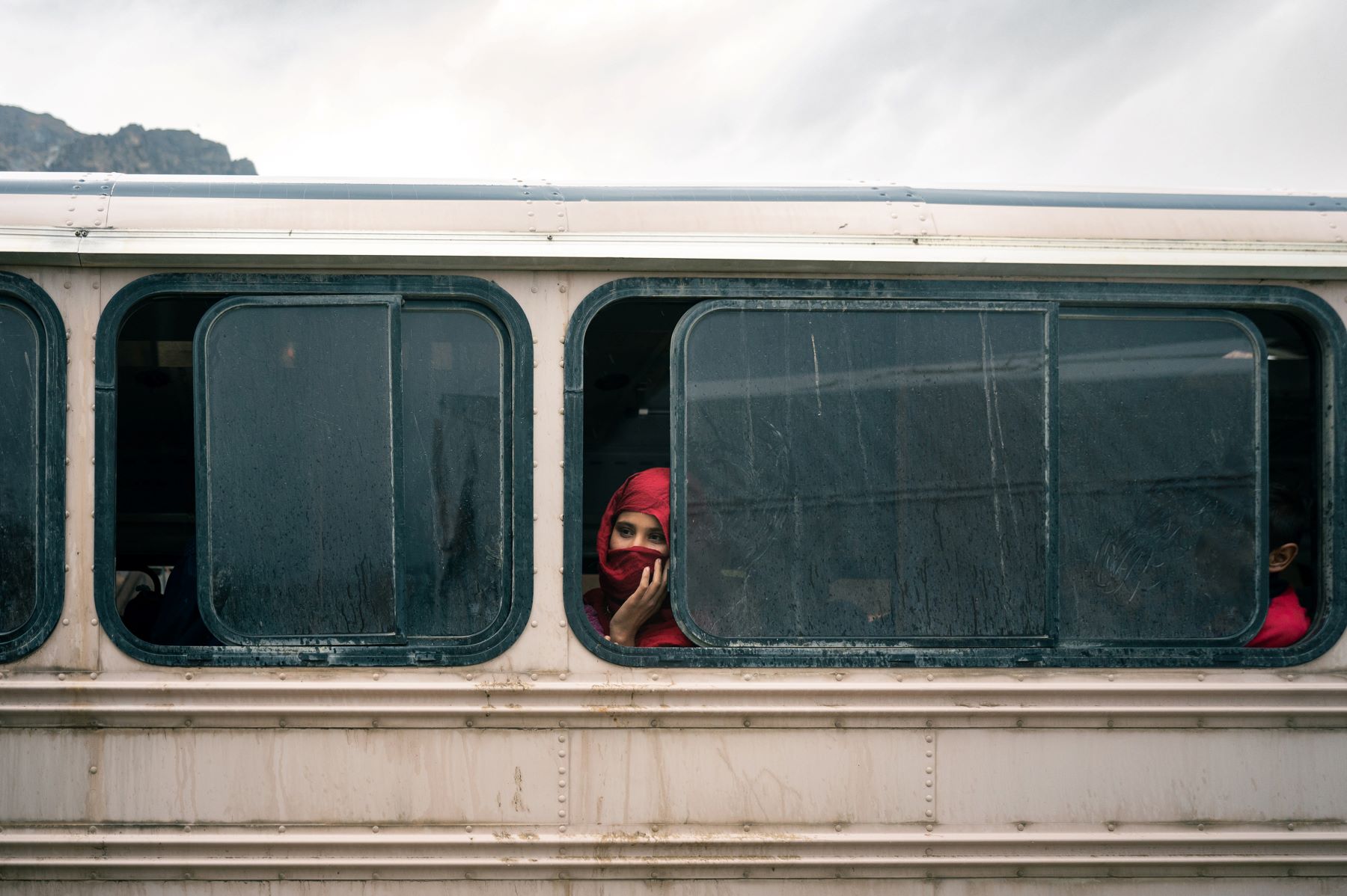 Woman sits in a bus going to a camp set up for returnees who have been deported or coerced into leaving Pakistan, at the Torkham border crossing in Nangarhar province, Eastern Afghanistan. Photo by The Washington Post.