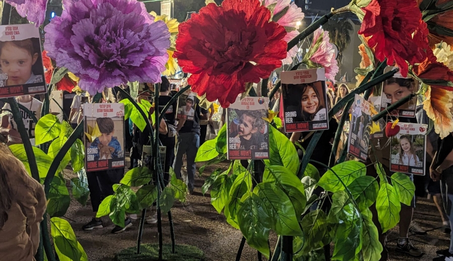 Header image: An installation in “Hostages Square” (official name “Tel Aviv Museum Plaza”), of adult human size flowers with signs of children hostages. Photo by Gil Naveh/Amnesty International Israel.