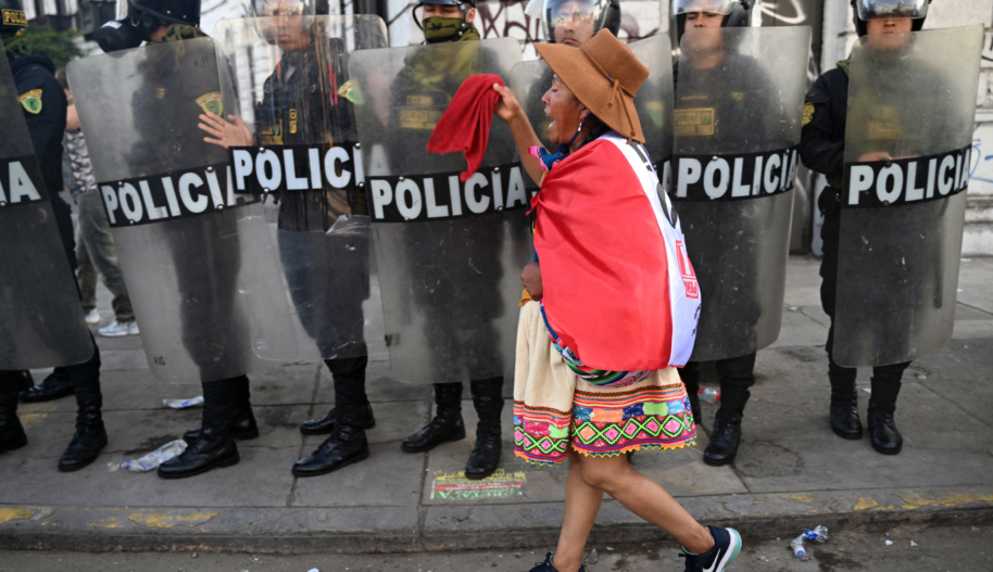 An Indigenous woman walks in front of riot police during a protest demanding the resignation of Peru's President Dina Boluarte in Lima on January 23, 2023.