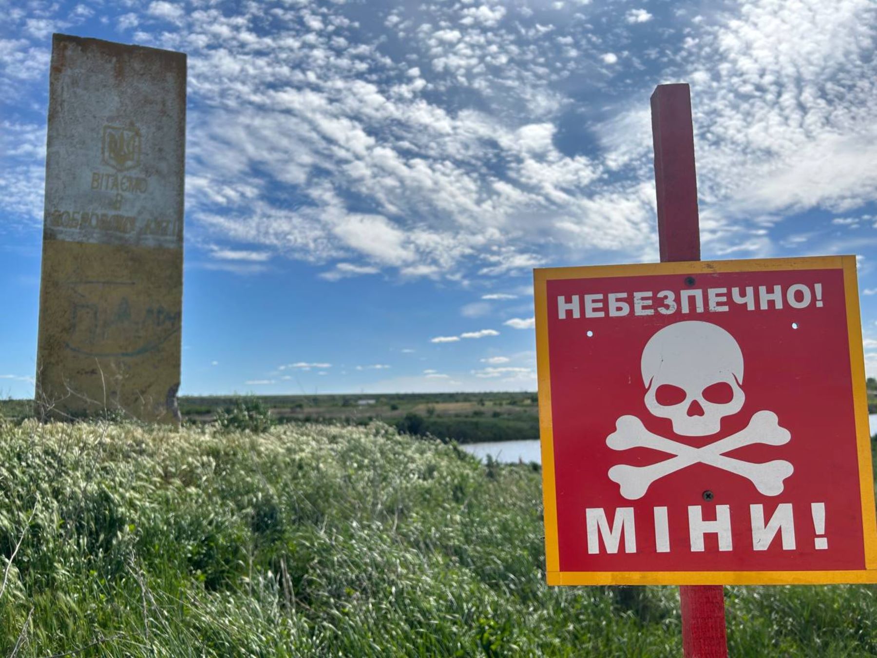 Mine sign by a river in in Kalynivka, Kharkiv oblast. © Amnesty International