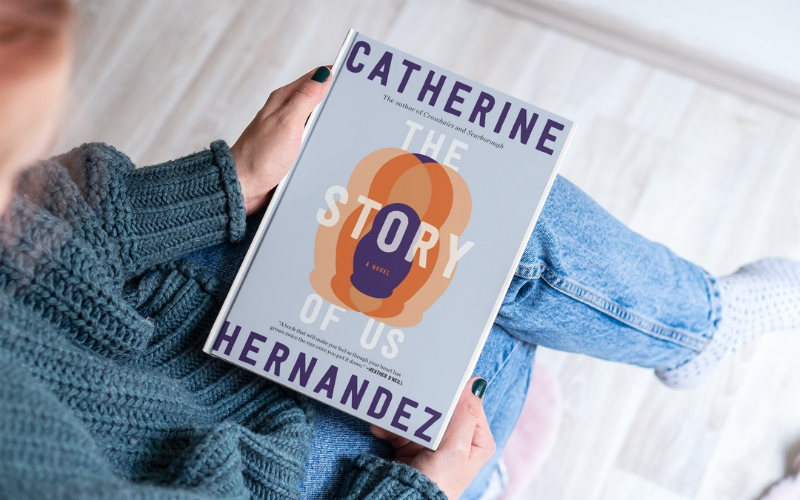 person holding a copy of the book, The Story of Us by Catherine Hernandez