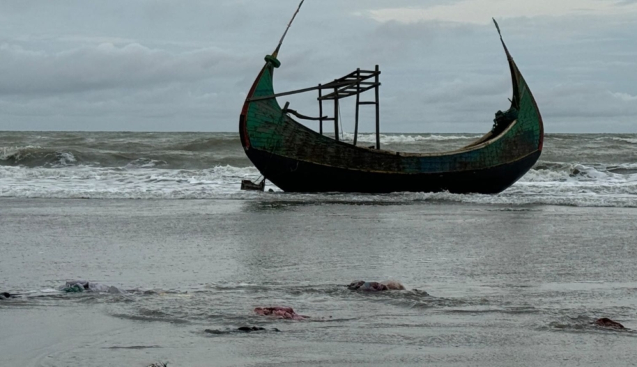 In the early morning of August 6, 2024, about 250 Rohingya survivors fled bomb attacks in Myanmar, crossing into Bangladesh in several boats via the Naf River. They arrived at Marine Drive near Teknaf in Bangladesh, where one of the boats capsized, resulting in the deaths of several Rohingya men, women, and children. This photo from August 6, 2024 shows one of the boats that carried the survivors. The foreground is strewn with clothes and sandals belonging to Rohingya who fled. © Shafiqur Rahman