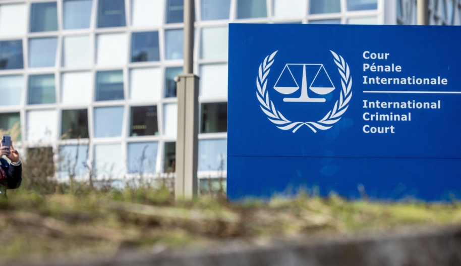 A young women taking a picture of a blue sign that reads "International Criminal Court."