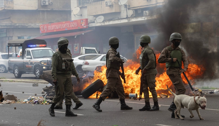 Anti-riot police officers with their dogs walk down Eduardo Mondlane Avenue past burning barricades made by protesters in Maputo, Mozambique on November 7, 2024.