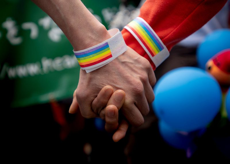 2 hand held together with rainbow on their bracelets