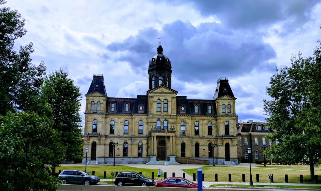 A limestone brick neo-Classical building on a cloudy but bright day.