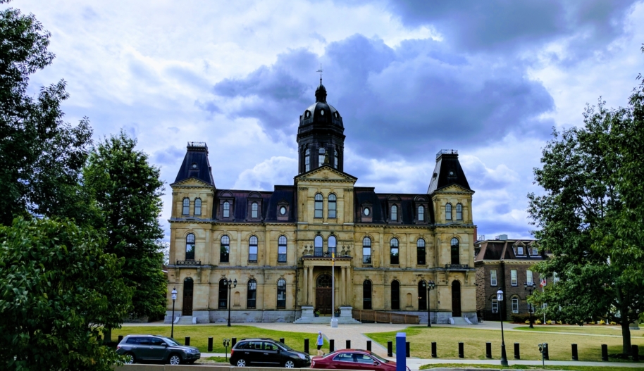 A limestone brick neo-Classical building on a cloudy but bright day.