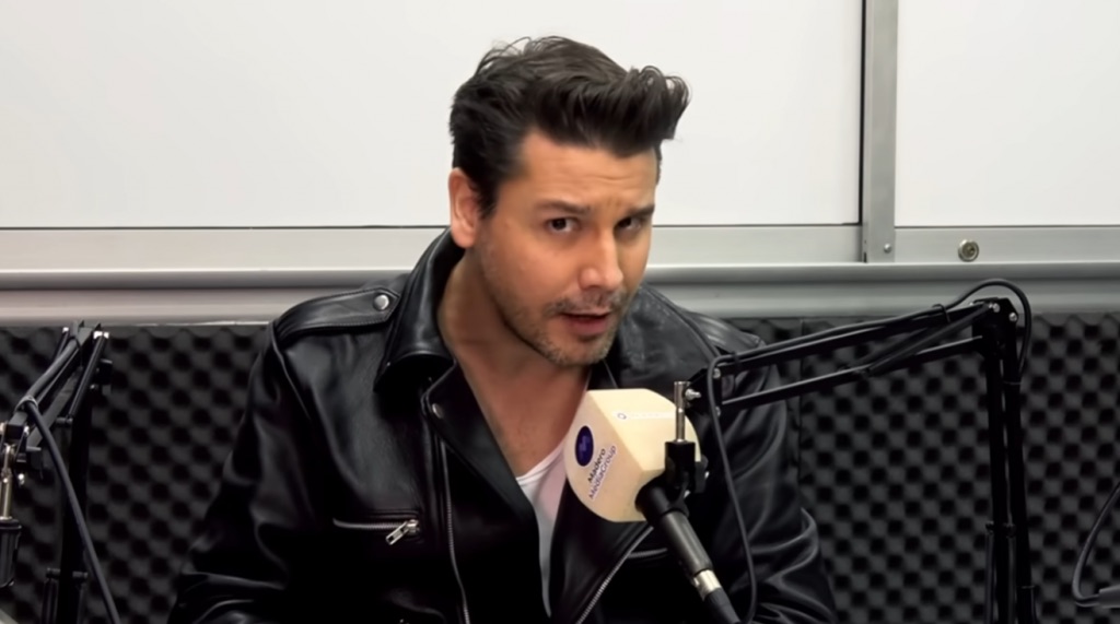 Man talking into a microphone wearing a leather jacket