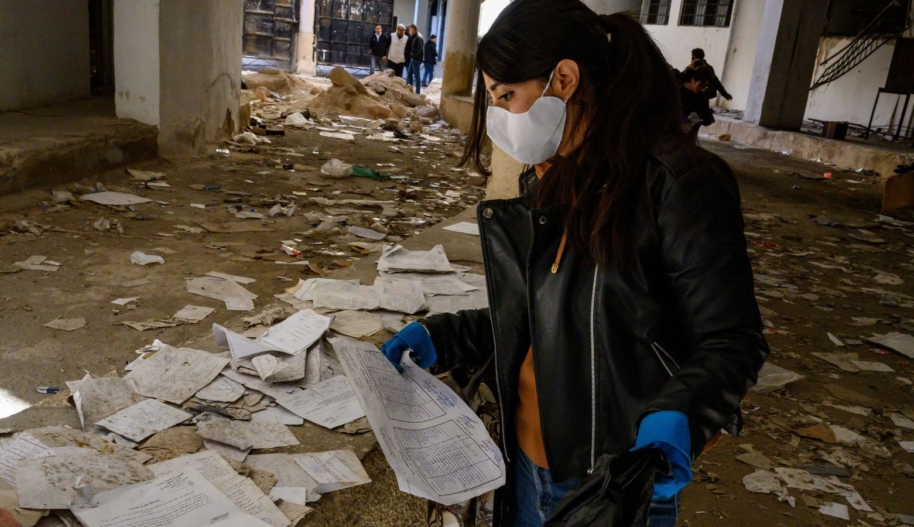 A volunteer collects documents to preserve, as Syrians search and inspect Sednaya Prison, where thousands of people were detained and tortured by the Assad regime, on December 14, 2024 in Damascus, Syria.