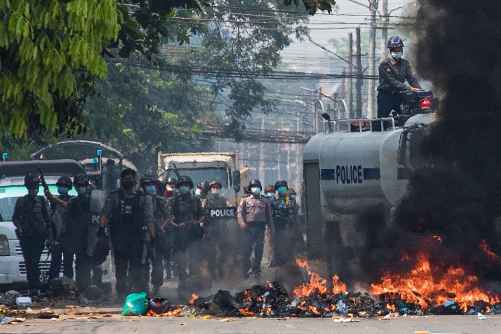 Security forces gather behind a burning barricade during a crackdown on protests against the military coup in Yangon on March 17, 2021. (Photo by STR / AFP) (Photo by STR/AFP via Getty Images)