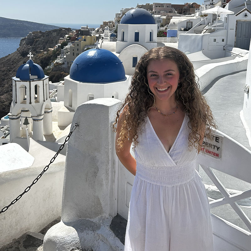 Young woman standing on balcony in front of European city background