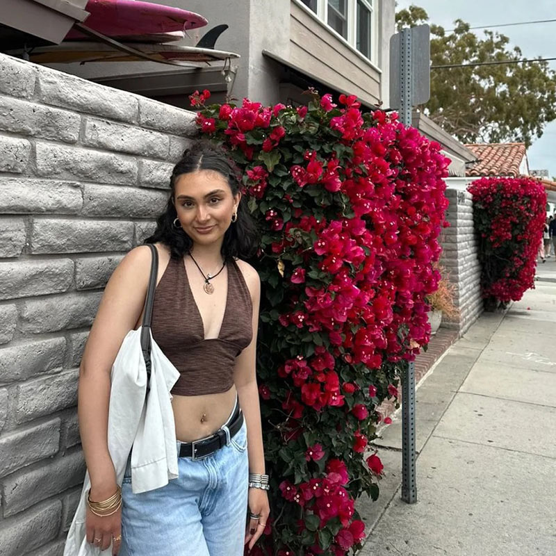 Young woman standing in front of brick wall with flowers