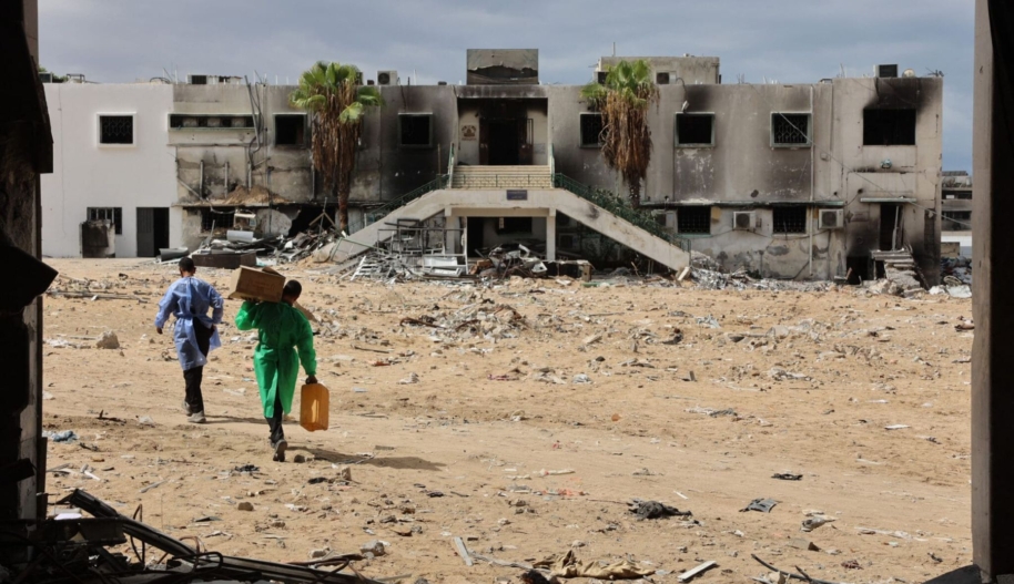 Men walk past a destroyed section of al-Shifa hospital in Gaza City on September 17, 2024. Omar Al-Qattaa/AFP via Getty Images.