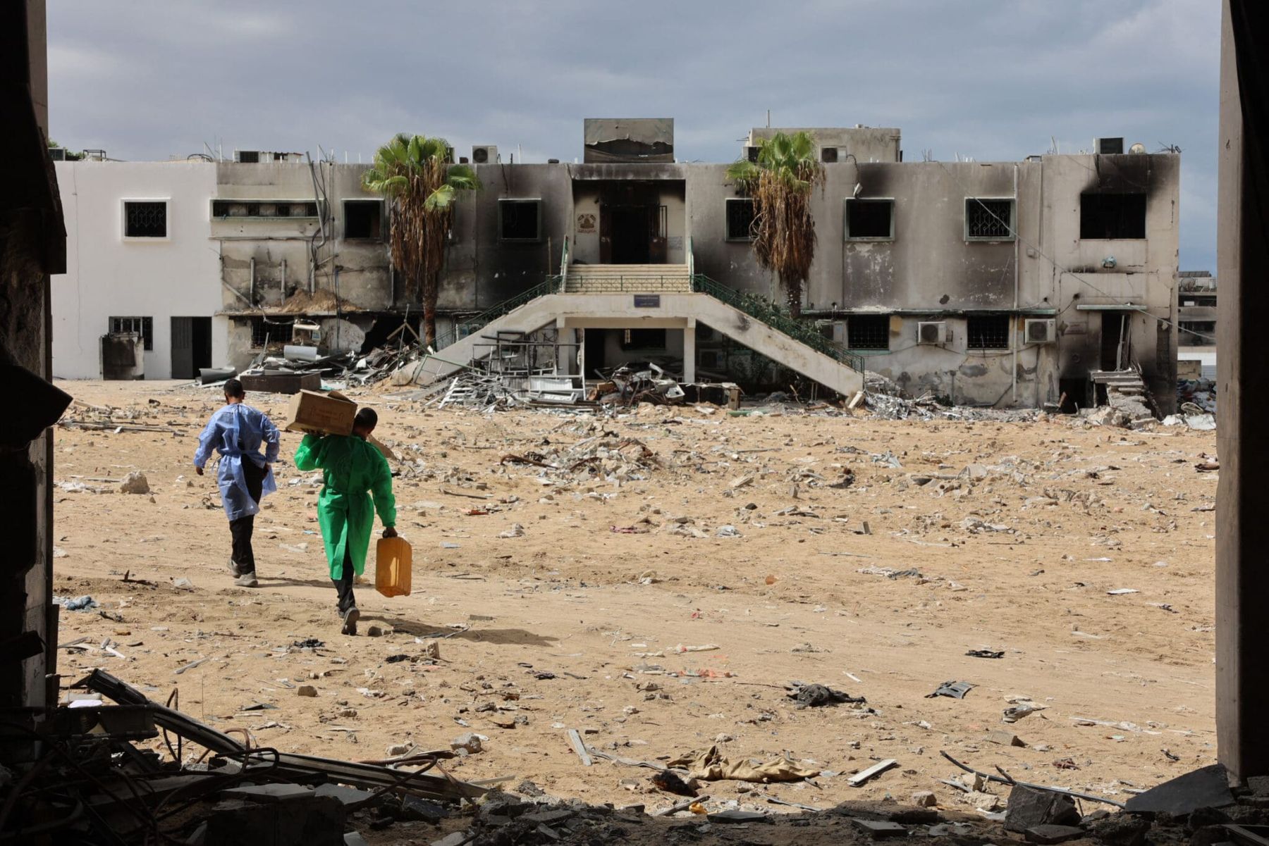 Men walk past a destroyed section of al-Shifa hospital in Gaza City on September 17, 2024. Omar Al-Qattaa/AFP via Getty Images.