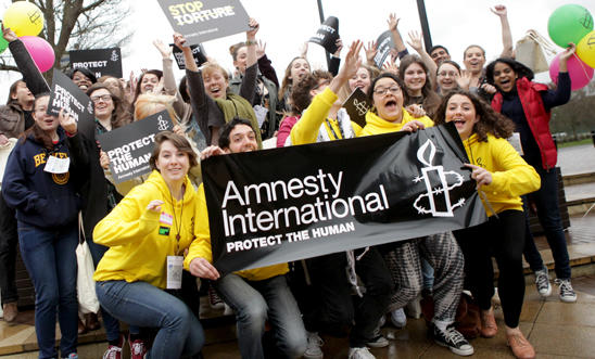 Amnesty supporters posing in front of an Amnesty International banner
