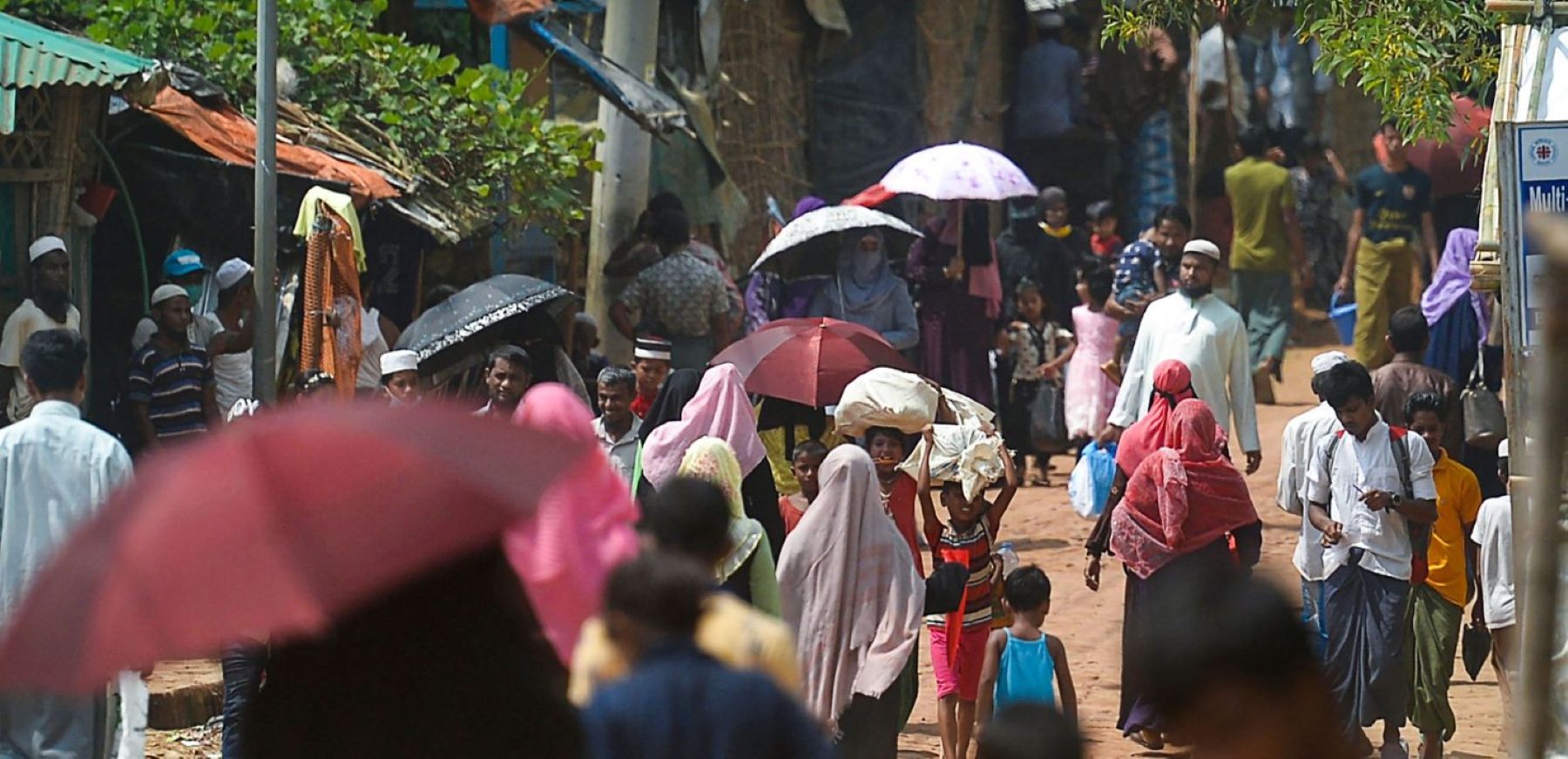 Rohingya refugees walk along a road near the office of slain community Rohingya leader Mohib Ullah, who was shoot dead by gunmen last month, at Kutupalong refugee camp in Ukhia on October 6, 2021. Photo by MUNIR UZ ZAMAN/AFP via Getty Images.