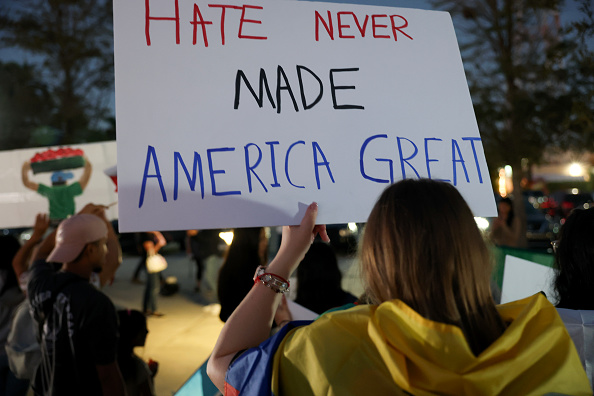 Woman holding up sign that reads "Hate never made America great"