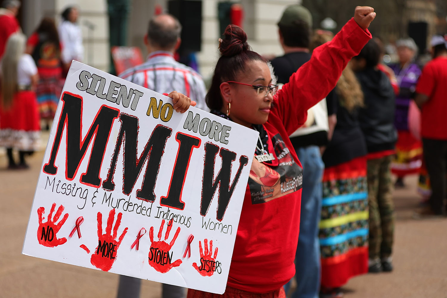 Woman protesting with sign reading "Silent No More - MMIW"