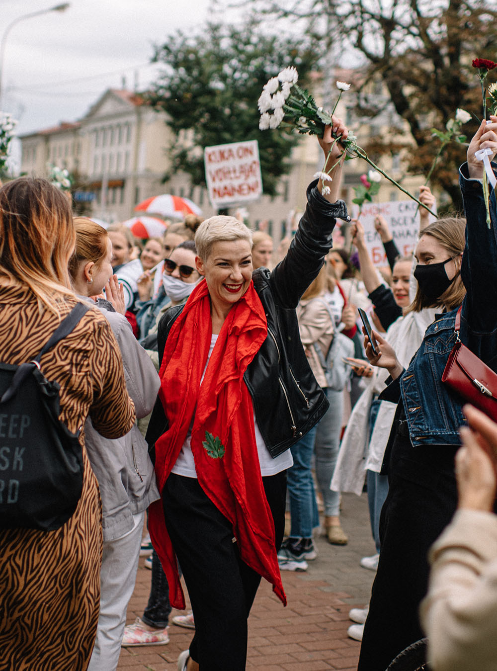 Woman celebrating in a crowd of people holding fist full of flowers up