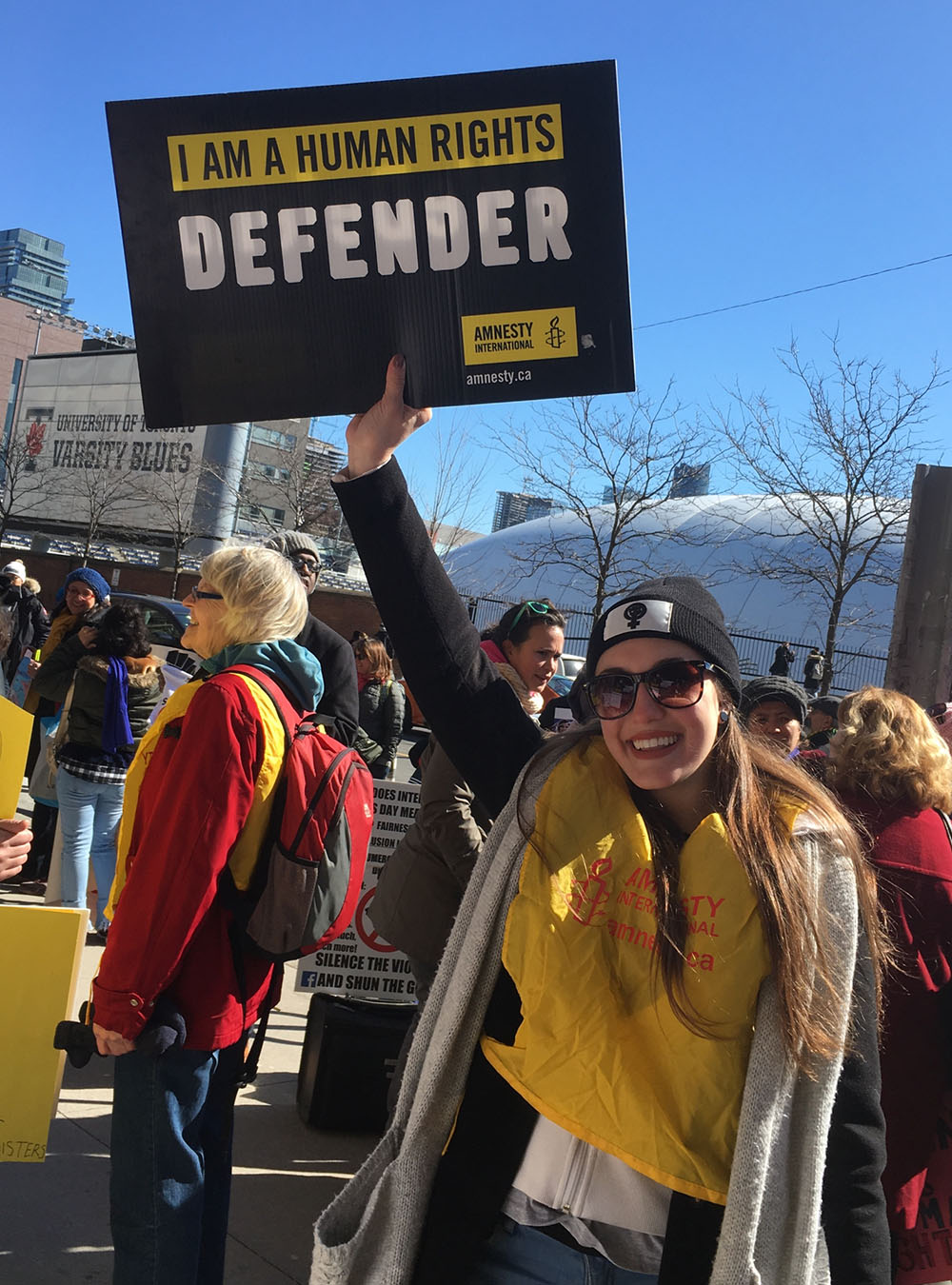 Woman in a rally holding up sign that reads "I am a human rights defender"