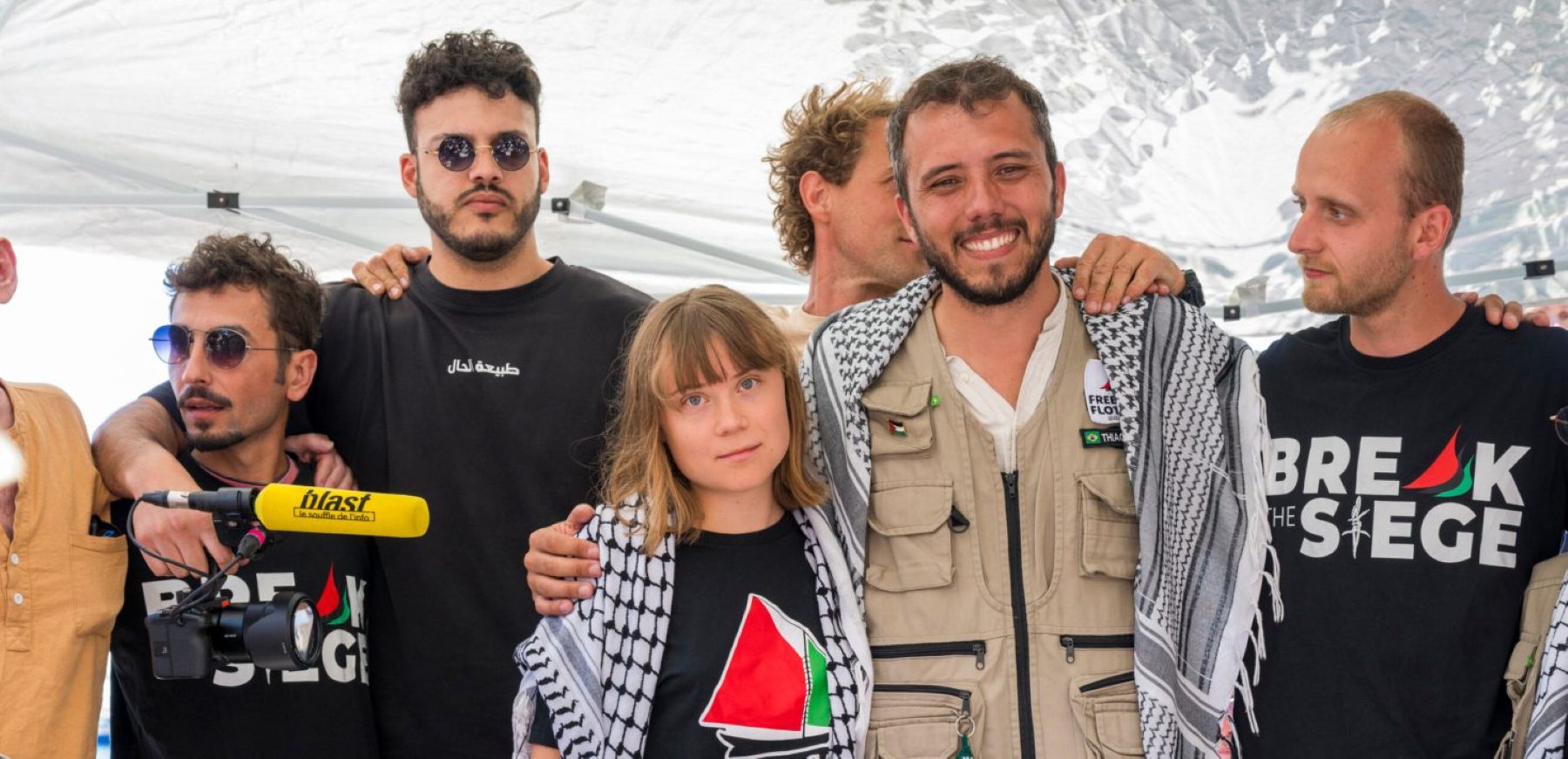 Eight members of the Madleen crew, including Greta Thunberg, pose for a photo. They are wearing t-shirts that read 'Break the Siege' and 'Ship to Gaza'. Photo by Fabrizio Villa/Getty Images.
