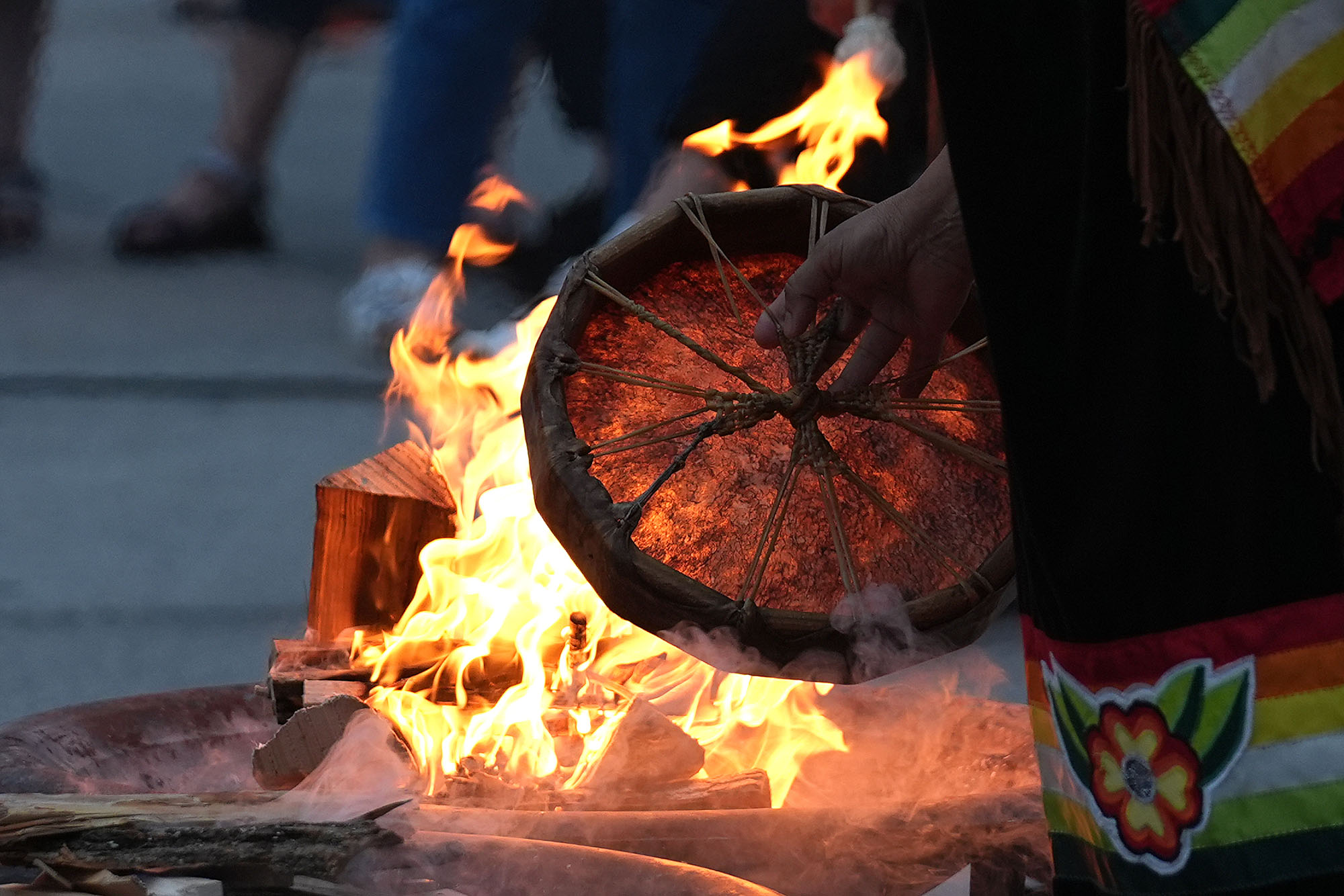 Heating a drum by the fire during the annual Sunrise Ceremony to mark National Indigenous Peoples Day