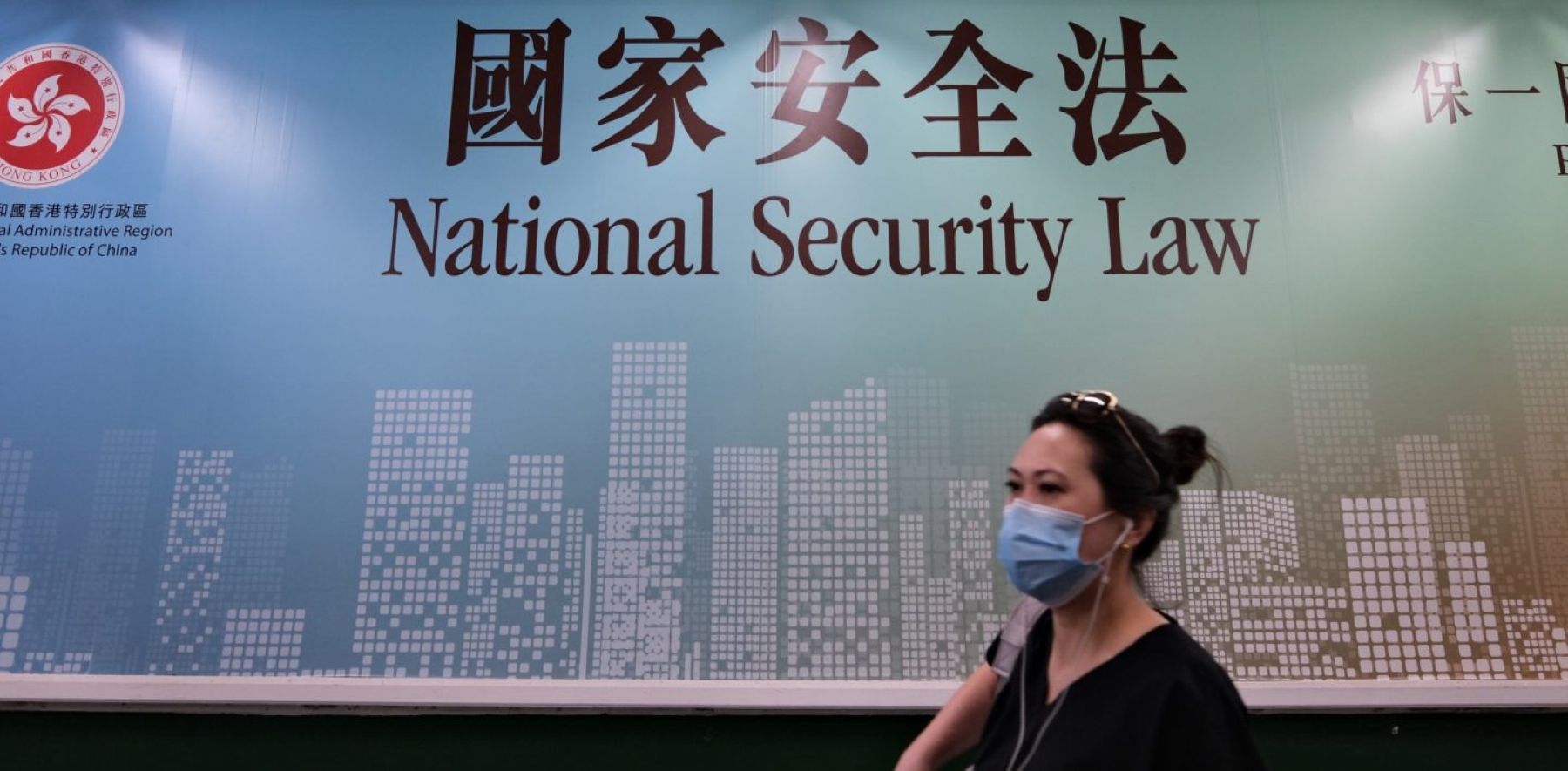 A woman walks past a poster for the National Security Law in Hong Kong on July 28, 2020. Photo by ANTHONY WALLACE/AFP via Getty Images.