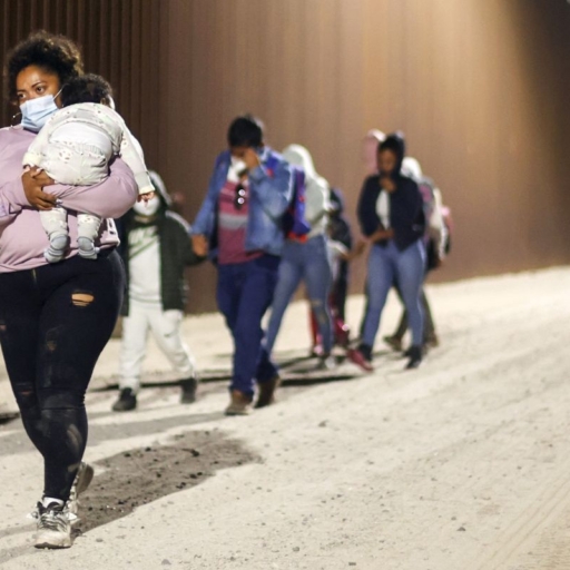 Immigrants walk along the U.S.-Mexico border barrier in the early morning hours on their way to be processed by the U.S. Border Patrol, after crossing from Mexico, on May 23, 2022 in Yuma, Arizona. Photo by Mario Tama/Getty Images.