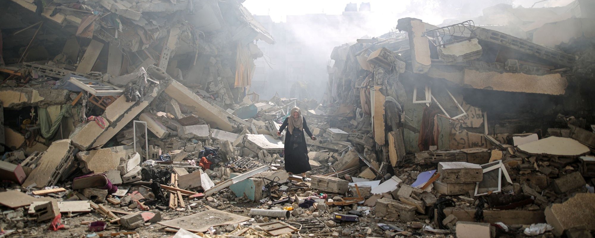 A woman walks through rubble of residential buildings after Israeli airstrikes at al-Zahra neighborhood in Gaza Strip on October 19, 2023. Photo by Mustafa Hassona/Anadolu via Getty Images.
