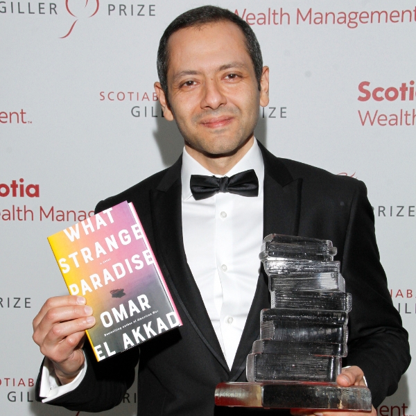 Omar El Akkad holding up his award and bestselling novel What Strange Paradise