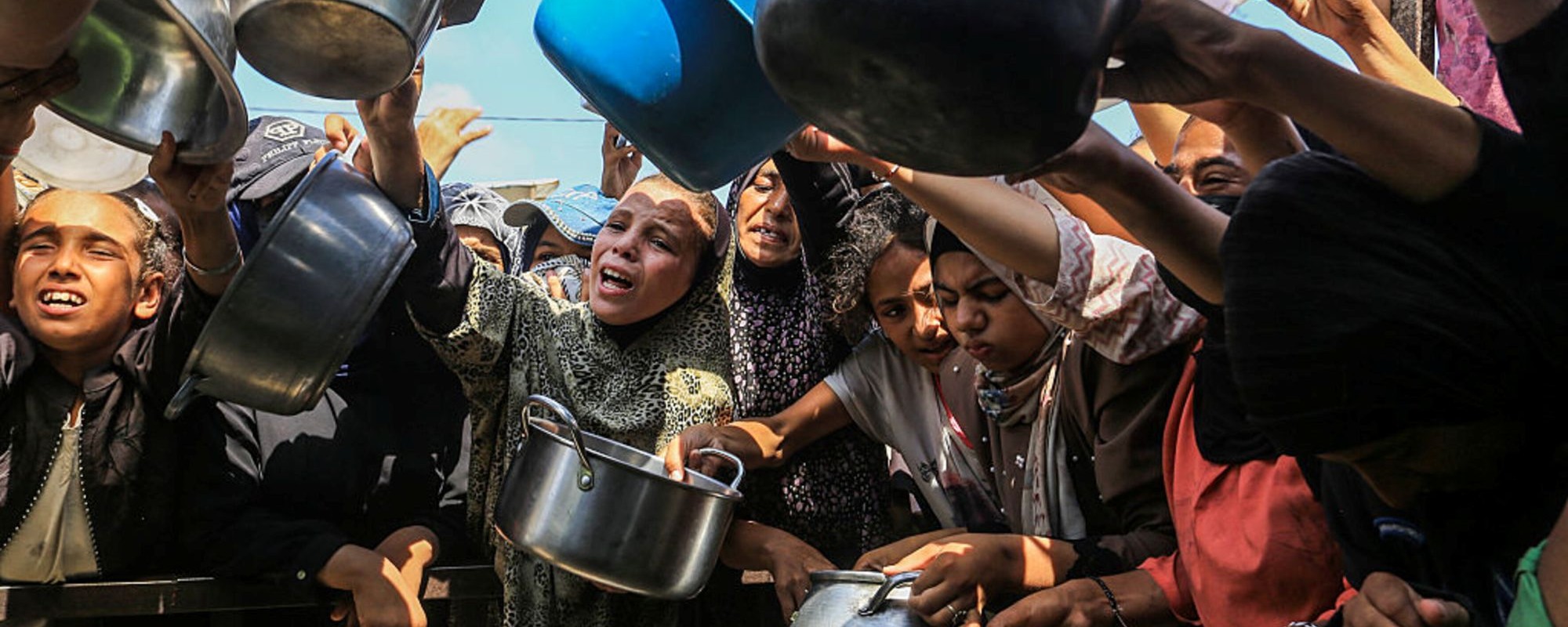 Palestinians, including children, who are struggling to access food due to Israel's blockade and ongoing attacks on the Gaza Strip, wait in line to receive hot meals distributed by the charity organization at Al-Mawasi area in Khan Yunis, Gaza on August 21, 2025. Photo by Abed Rahim Khatib/Anadolu via Getty Images.