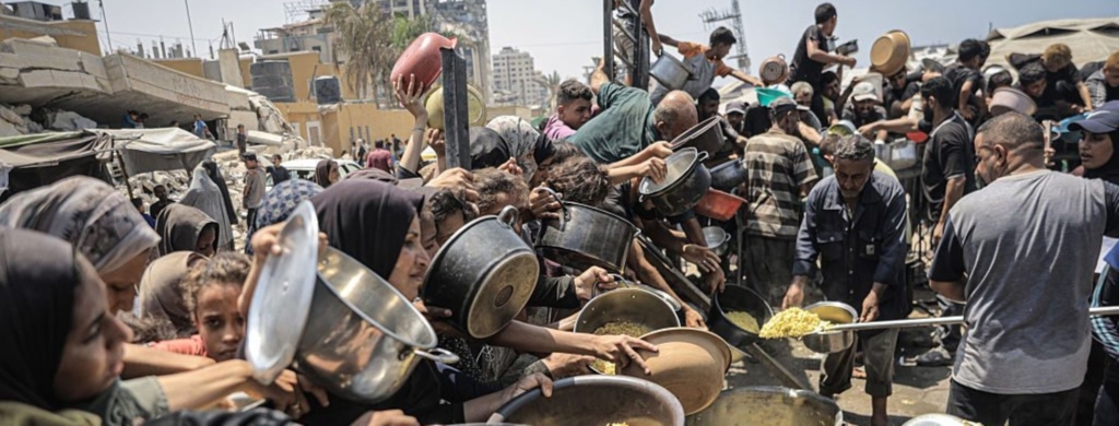 Palestinians wait with pots in their hands as a charitable organization distributes food to Palestinians suffering food crisis under Israeli blockade in Gaza City, Gaza on August 14, 2025. Photo by Ahmed Jihad Ibrahim Al-arini/Anadolu via Getty Images.