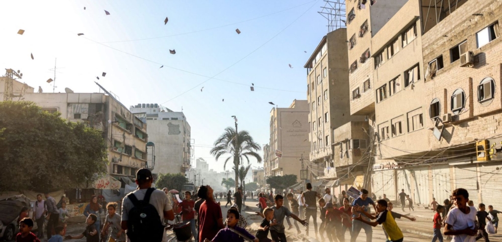 People watch as leaflets dropped by the Israeli military, urging evacuation south to al-Mawasi, land in Gaza City on September 9, 2025. Photo by OMAR AL-QATTAA/AFP via Getty Images.