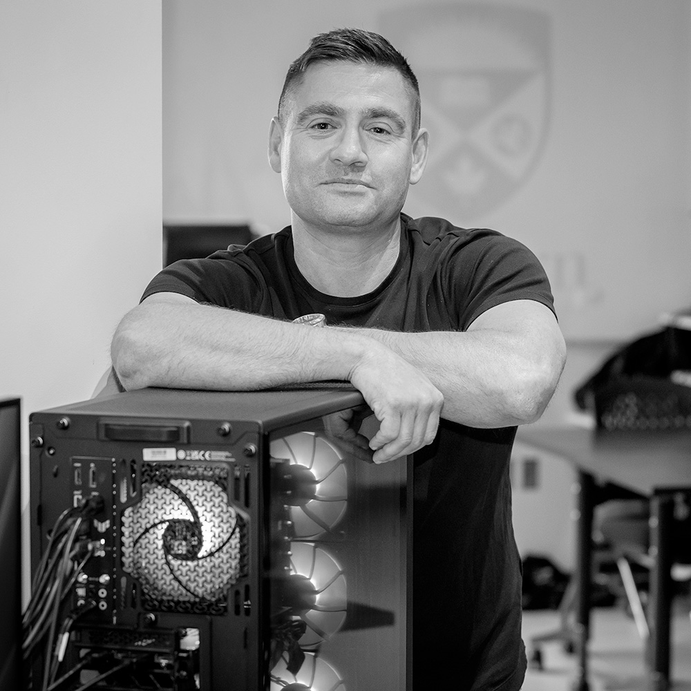Chris Arsenault standing behind a computer box with arms on top of it.