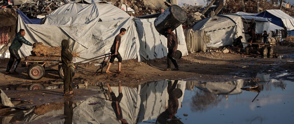 A displaced Palestinian man pulls a cart after heavy rain in Jabalia city, northern Gaza Strip, on November 25, 2025. Photo by Omar AL-QATTAA / AFP via Getty Images.