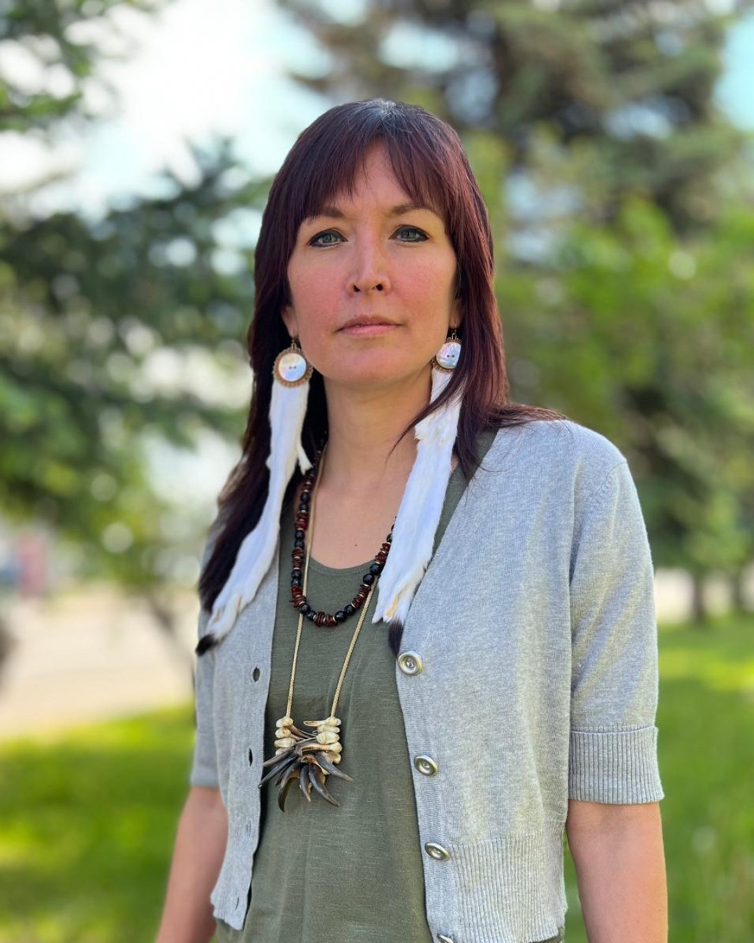 Molly (aka Sleydo') looks defiantly at the camera. She is a red haired woman wearing long earrings and a beaded necklace.