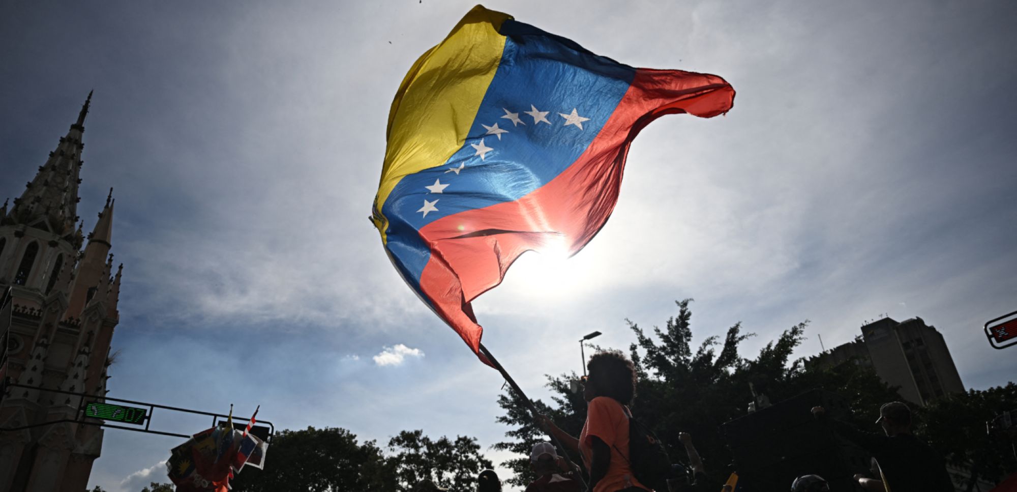 A person flutters a national flag in Caracas on January 3, 2026, after US forces captured Venezuelan leader Nicolas Maduro. Photo by Federico PARRA / AFP via Getty Images.
